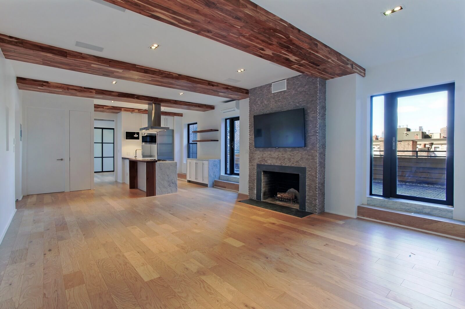 The living room decorated in a loft style looks impressive thanks to the right arrangement of all the main functional elements around the perimeter of the living room walls. A beautifully decorated fireplace adds some mystery to the entire interior contrasting perfectly with contemporary household appliances. The living room is decorated in calm warm gray, white, and brown tones, evoking a feeling of warmth, coziness, comfort, and tranquility. Try the best interior design service from one of the leading NYC design studios and appreciate the high-quality of its work done!