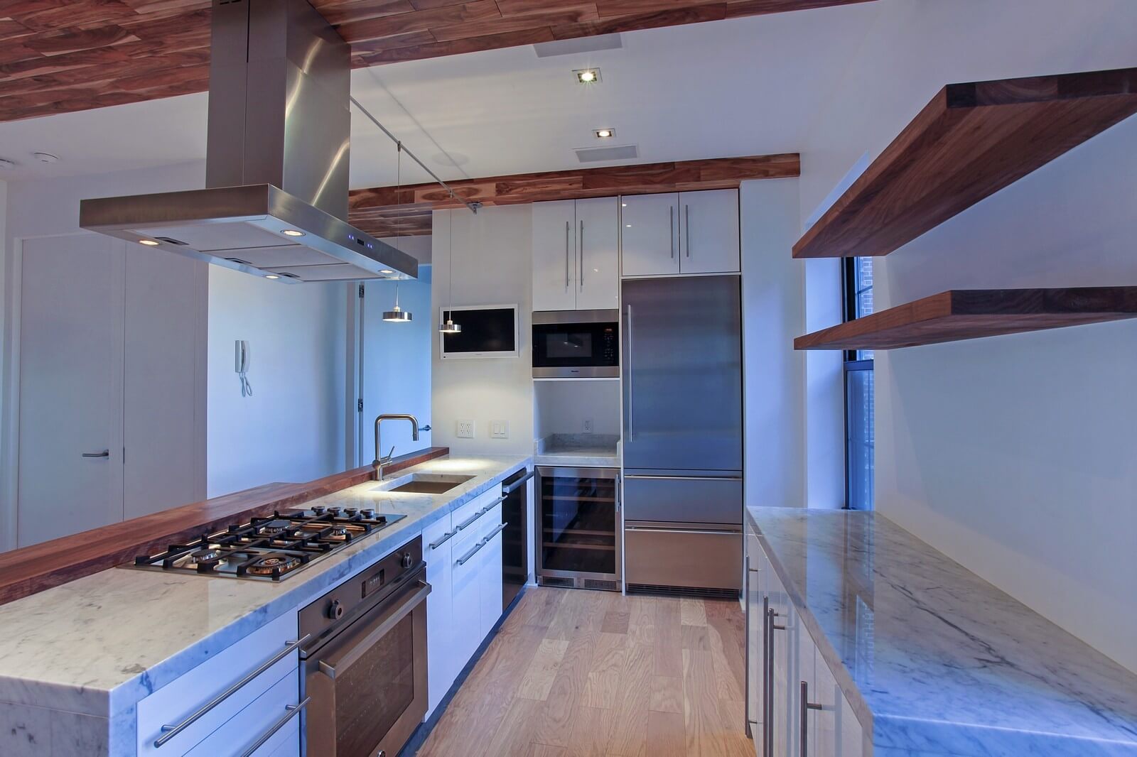 A U-shaped kitchen is known to be the perfect solution for rectangular spaces like this. The most important functional elements are all located around the perimeter of the room. The kitchen is equipped with several types of lighting: general lighting built into the ceiling, pendant lamps, and lamps built into the kitchen furniture. The interior design is done in white, brown and gray tones, hinting at comfort, warmth, tranquility, good appetite, and wonderful relaxation. The Grandeur Hills Group interior design service is the key to your home interior design of high-quality. Be sure to contact our managers and order the best service in NYC.